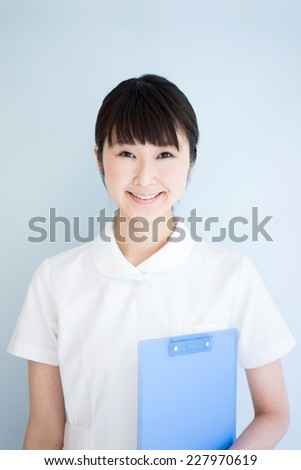Young nurse woman holding file against pale blue background 