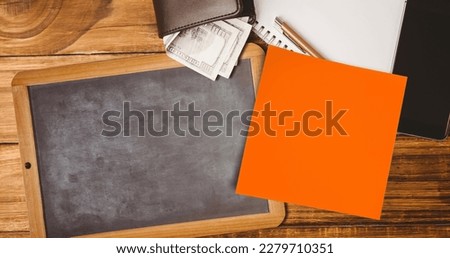 Image of memo note with copy space over chalkboard and wallet on desk. national clean your desk day concept digitally generated image.