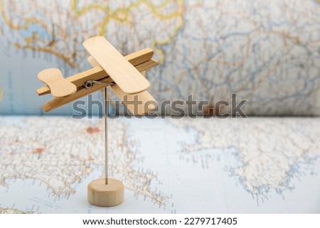Wooden plane made with ice cream sticks and a clothespin, flying over a map Royalty-Free Stock Photo #2279717405
