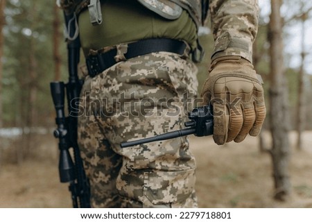 a military man in a camouflage uniform and tactical gloves holds a walkie-talkie. communication of the Ukrainian army during the war. Royalty-Free Stock Photo #2279718801