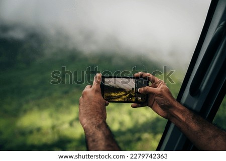 a person photographing a landscape using a mobile phone with an out of focus background. High quality photo