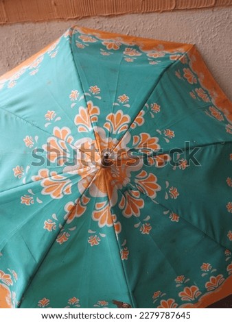A colorful and patterned umbrella is being sun-dried on the bicycle