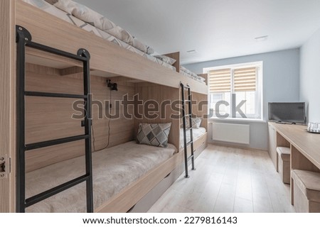 Hostel dormitory beds arranged in dorm room with white plain bunk bed in dormitory.Hostel dormitory have many beds arranged in one room. Clean hostel small room with wooden bunk beds. small hotel. Royalty-Free Stock Photo #2279816143