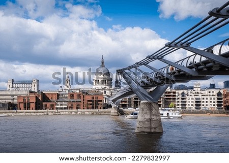 View of River Thames and Millennium bridge leading towards St. Paul Cathedral and buildings of the other side; sky on the background