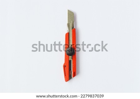 A utility knife in red on a white background
