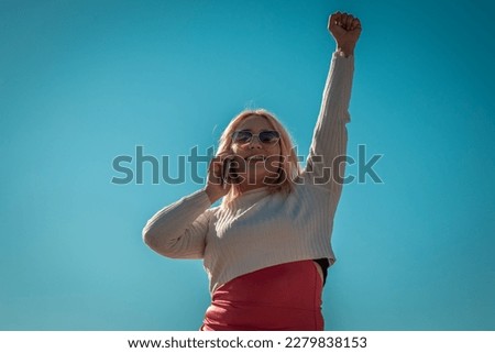 young beautiful plus size woman happy with phone and gesture of victory or success