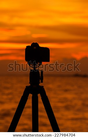 Camera silhouetted against the sea.