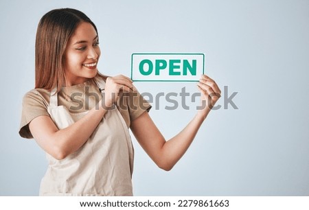 Coffee shop, small business and woman holding an open sign in studio on a gray background for hospitality. Cafe, startup and management with a female entrepreneur indoor to display advertising