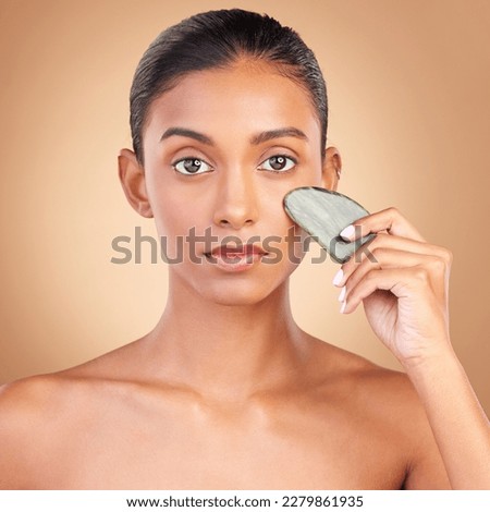 Skincare, beauty and portrait of Indian woman with gua sha, facial treatment and wellness with spa stone. Salon, dermatology and girl on brown background with cosmetics, face massage and luxury tools