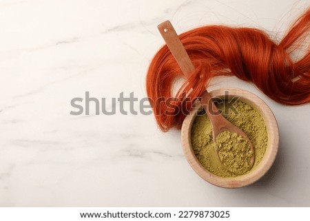 Bowl of henna powder and red strand on white marble table, flat lay with space for text. Natural hair coloring