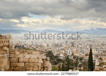 View on Athens from Pantheon on winter during cloudy cold day with snow on the mountain in background