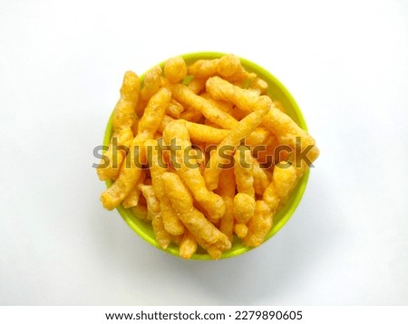 Crunchy cheese flavored puffed corn snacks in a green bowl isolated on white background Royalty-Free Stock Photo #2279890605
