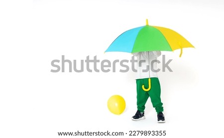 isolated a little boy in green pants hides under umbrella 