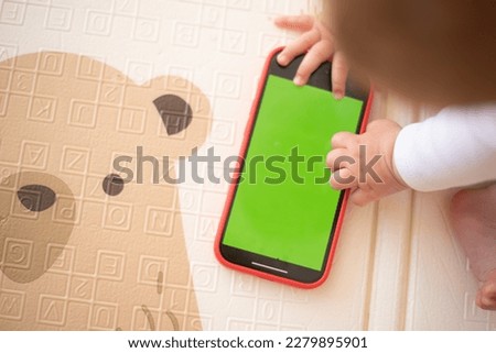 selective focus, Hands of baby touch and play phone with green screen. Baby study new technology, top view. Copy space for text