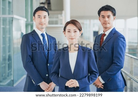 Businessmen and women standing side by side in an office corridor