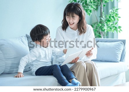 mother and boy sitting on the sofa and reading picture book Royalty-Free Stock Photo #2279900967