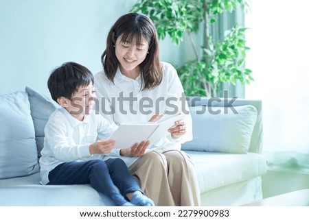 mother and boy sitting on the sofa and reading picture book Royalty-Free Stock Photo #2279900983