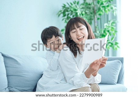 mother and boy sitting on the sofa and reading picture book