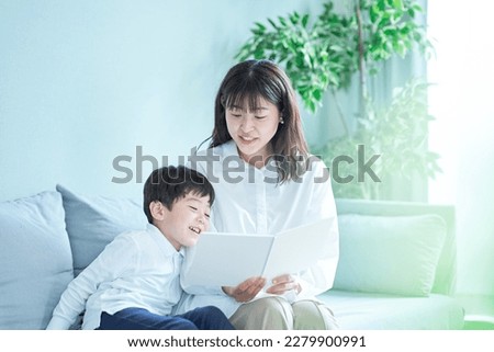mother and boy sitting on the sofa and reading picture book