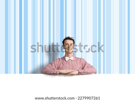 Young funny guy in checked shirt behind blank white banner