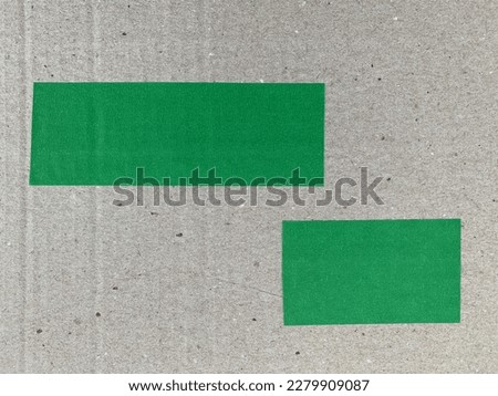 2 strips of green masking tape on corrugated cardboard with real shadow. Top view of adhesive tape, label or paper tag. Stickers close up with copy space for text or image. Abstract background