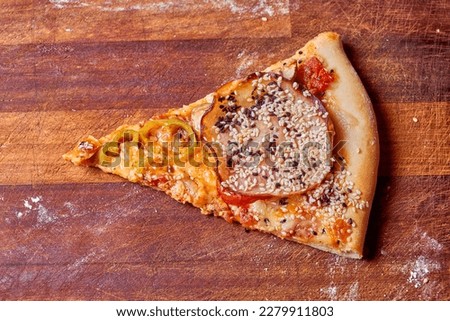 Slice of fresh pizza on a wooden surface.                               