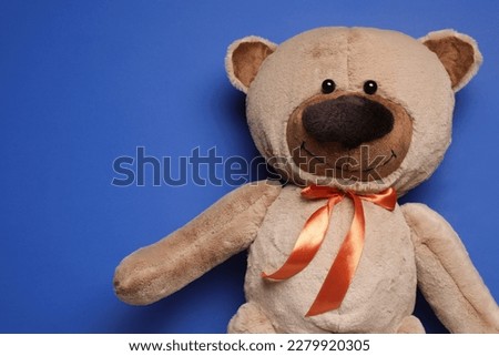 Cute teddy bear on blue background, top view. Space for text