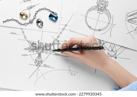 Jeweler drawing sketch of elegant necklace on paper, closeup