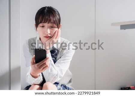 A high school girl who is depressed while looking at her phone Royalty-Free Stock Photo #2279921849