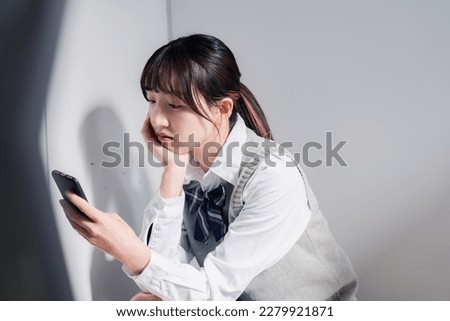 A high school girl who is depressed while looking at her phone Royalty-Free Stock Photo #2279921871