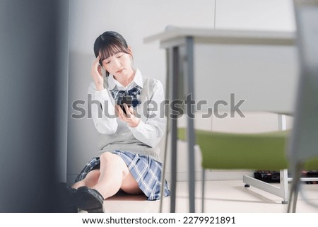 A high school girl who is depressed while looking at her phone Royalty-Free Stock Photo #2279921891