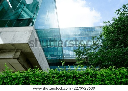 Sustainble green building. Eco-friendly building in modern city. Sustainable glass office building with tree for reducing carbon dioxide. Office with green environment. Corporate building reduce CO2.  Royalty-Free Stock Photo #2279923639