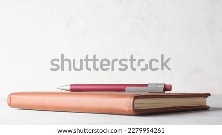 pencil on a note book or leather diary placed on white table top against a textured wall background, education and journaling concept with copy space and soft-focus