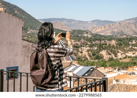 Tourist taking picture of Finestat. Travel woman using small camera to take a landscape photo. Finestat, Alicante province, Costa Blanca, Spain. Solo travel, singles vacation