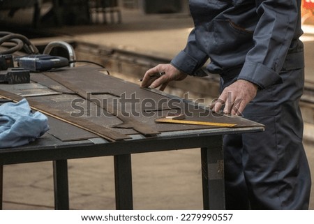 A craftsman makes parts from wood on a table in the workshop