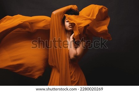 Black woman, art and fashion, fabric movement on dark background with beauty and aesthetic motion. Flowing silk, fantasy and artistic, serious African model in brown creative designer dress in studio