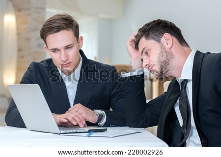 Looking for a solution. Two businessmen are working with laptop and looking for the solution of current project issues