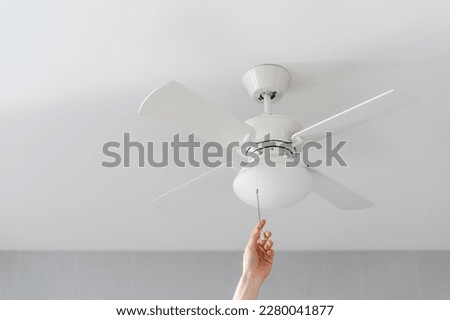cropped shot of female hand pull switch of ceiling fan with lamp on white background with copy space, room cooling and ventilation concept Royalty-Free Stock Photo #2280041877