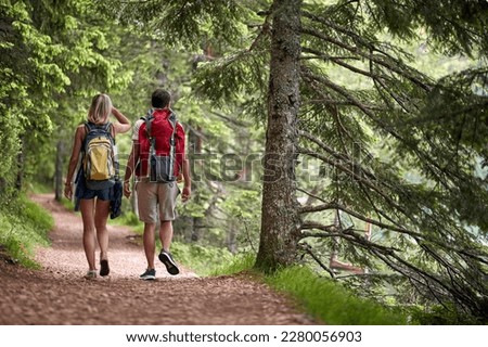 A couple is hiking the forest path on a beautiful day. Trip, nature, hiking Royalty-Free Stock Photo #2280056903