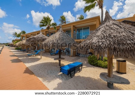 Beautiful view of hotel from coastline of sandy beach with sun loungers and umbrella sun. Aruba.