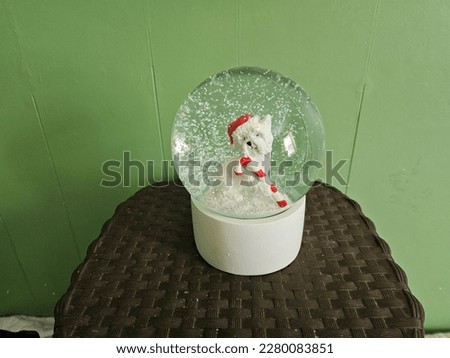 A west highland terrier snow globe sitting on a basket.