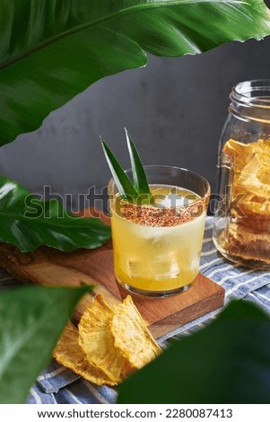 Special cocktail of pineapple, rum and mezcal with garnish chili and pineapple plants garnished with dried fruit in a kitchen with plants, no people Royalty-Free Stock Photo #2280087413