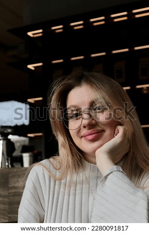 young pretty woman in glasses in cafe relaxing drinking latte and smiling seductively