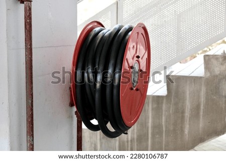 Red fire hose reel hanging on a wall. Selective focus
