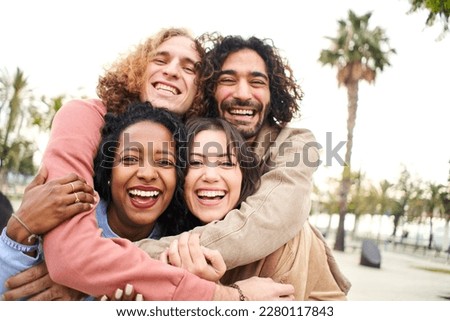 Group of four multi-ethnic young friends having fun. Smiling cheerful people looking at the camera outdoors. High quality photo