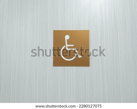 Symbol of disabled person on wheel chair with color gold square on wooden toilet door hospital