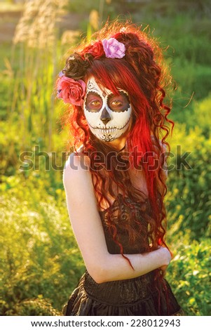 Gothic Beauty; A redhead lady in Mexican Mask with flowers in her hair posing for a photo