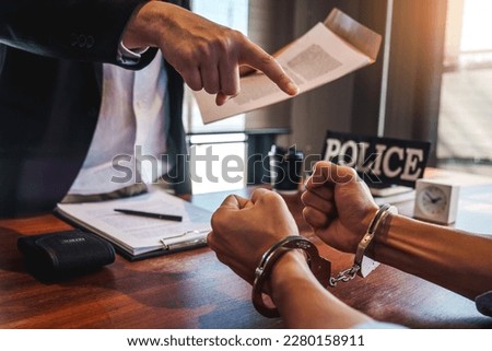 Law enforcement officer interrogating Criminals male with handcuffs in the investigation room Police officer interviewing after committed a crime Royalty-Free Stock Photo #2280158911