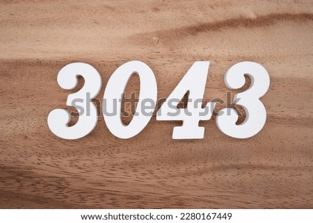 White number 3043 on a brown and light brown wooden background.
