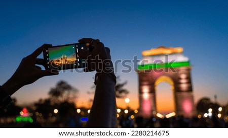 Unrecognizable hand-capturing photo of The India Gate, a war memorial located at Kartavya path, New Delhi, India